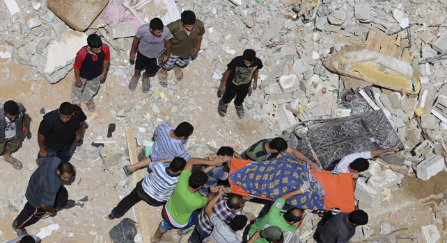 Palestinos trasladan el cuerpo de una mujer encontrado entre los escombros de una casa en Gaza.