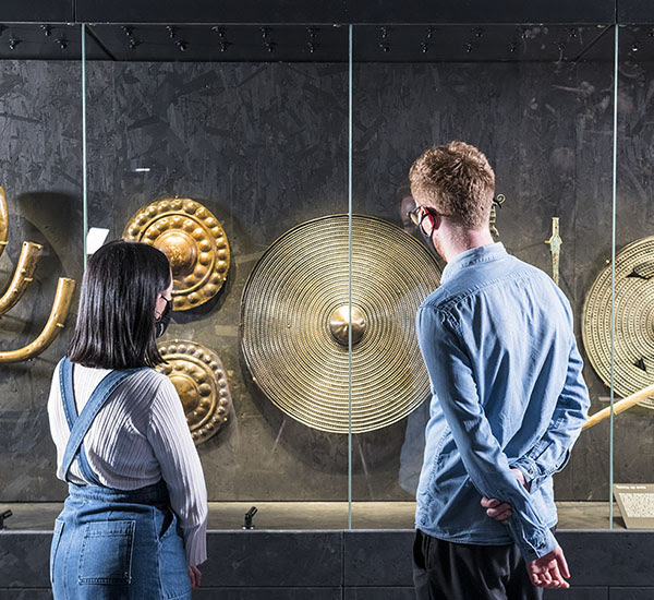 Visitors inside 'The world of Stonehenge' looking at round shields.