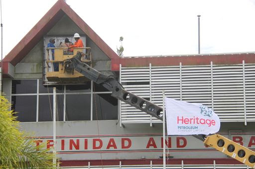 Contractors replace Petrotrin sign and flags with those bearing Heritage Petroleum at the company’s administration building in Santa Flora, yesterday.