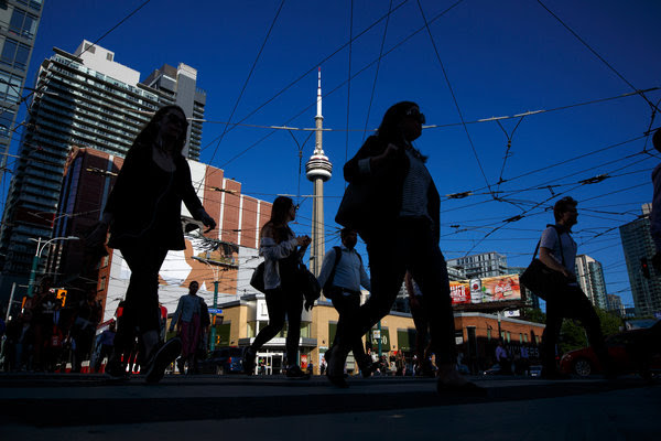 Pedestrians silhouetted against the CN Tower in Toronto.