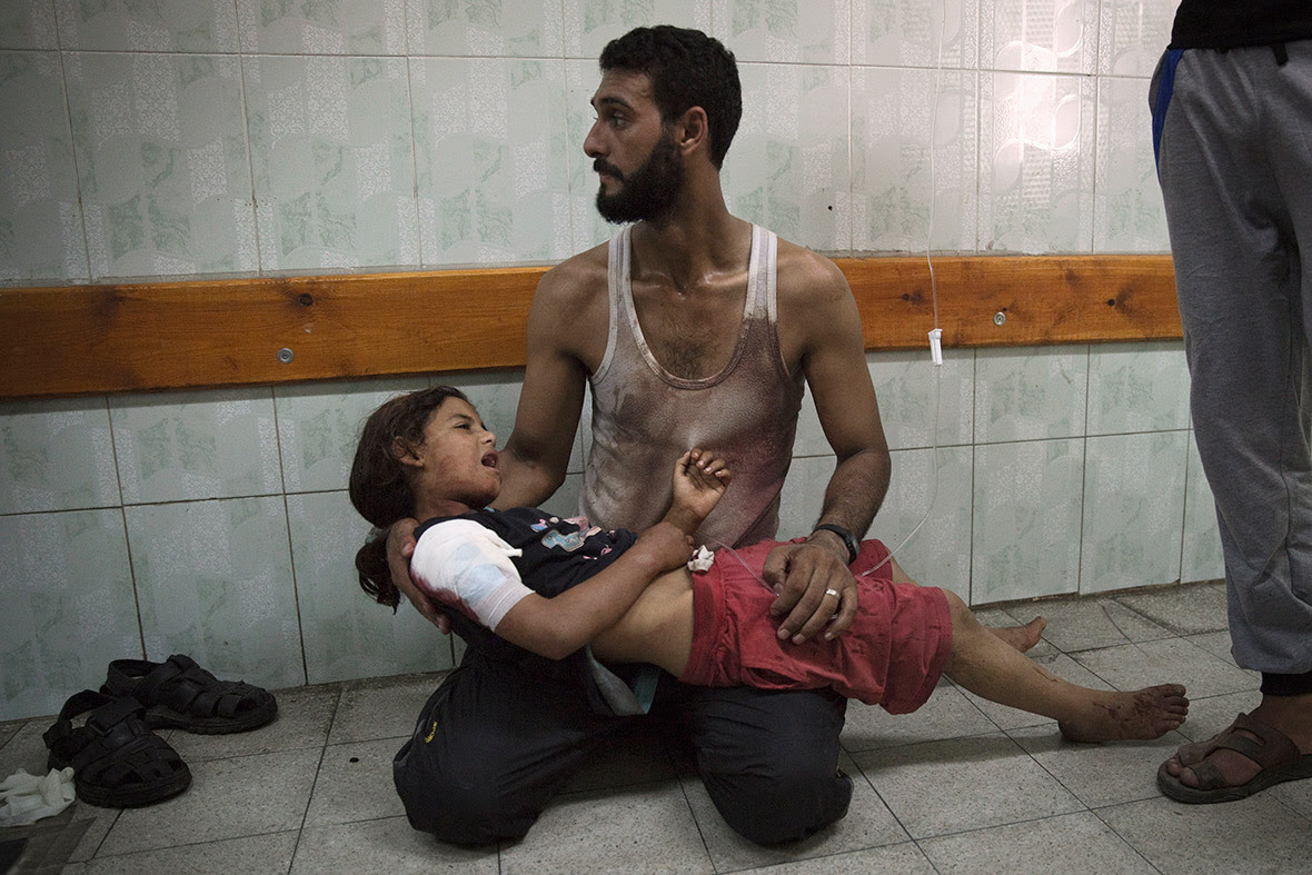A man holds a girl, whom medics said was injured in the Israeli shelling of the school