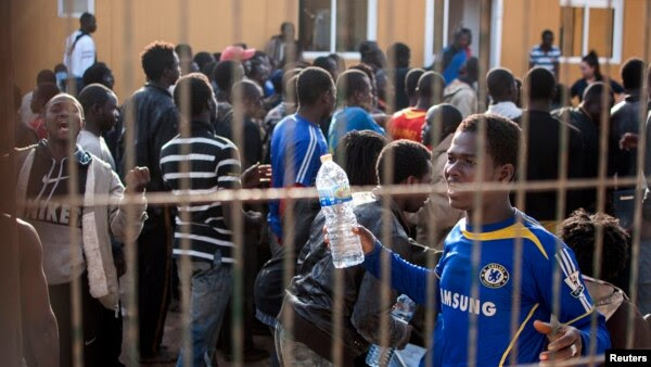 Would-be immigrants react from behind the fence of a temporary immigrant holding center after crossing the border from Morocco to Spain's north African enclave of Melilla March 18, 2014.