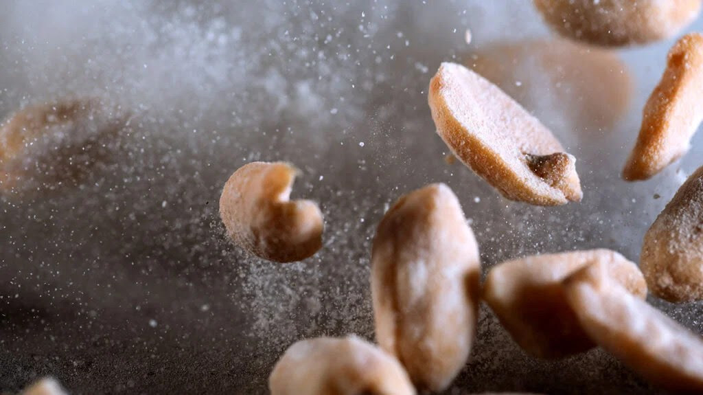 A close up of salted peanuts being tossed in the air