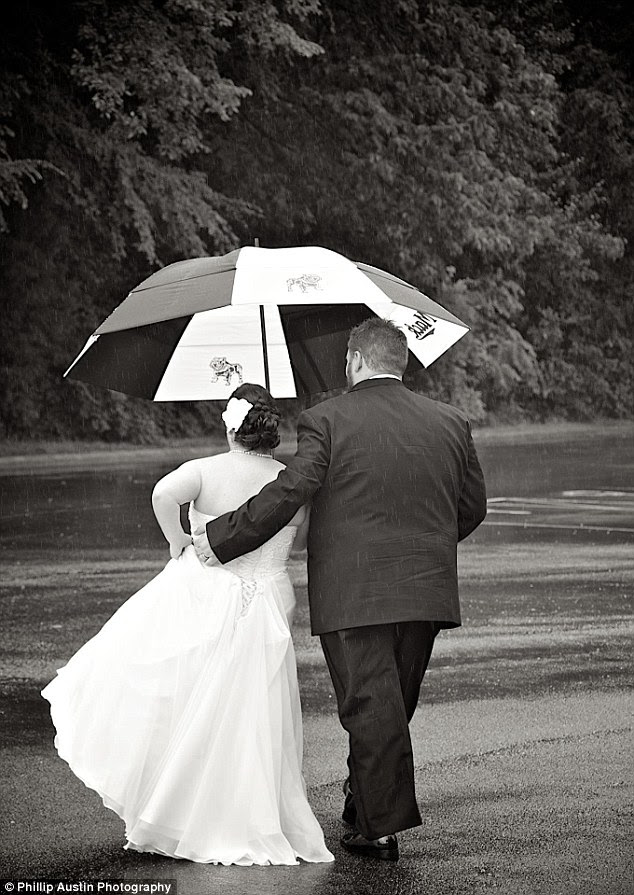 Devotion: Two newlyweds hold  each other lovingly as they walk together in the rain