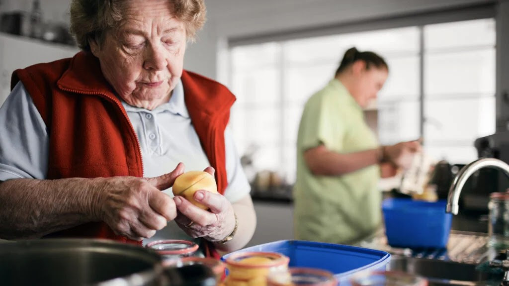 older woman peeling fruit in a kitchen