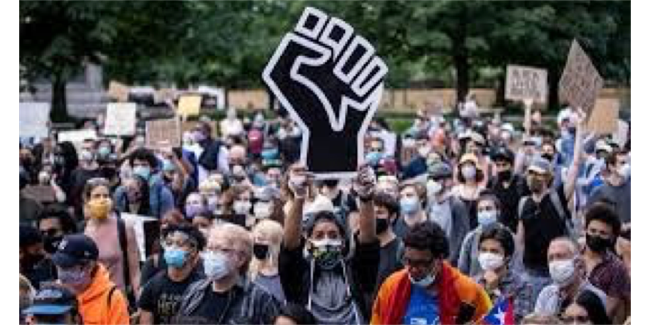 Image of group of protestors, one person holding a sign of a black fist.