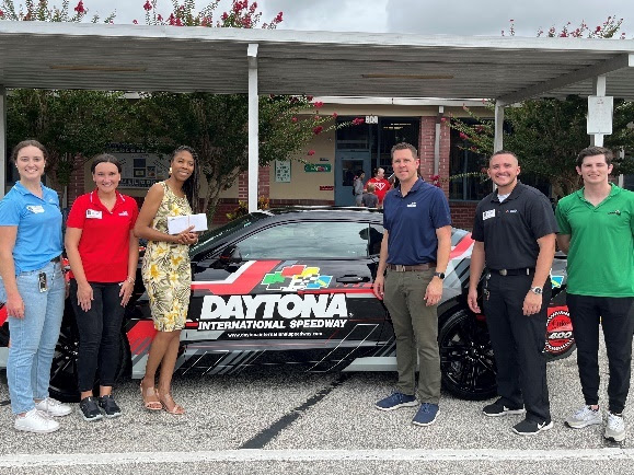 A group of people standing next to a car
Description automatically generated with medium confidence