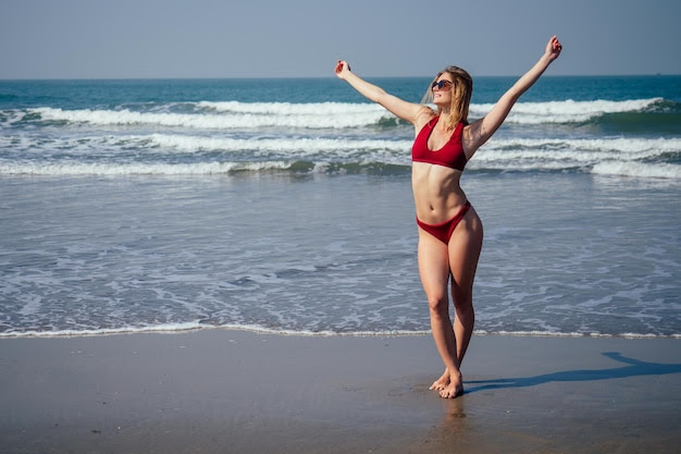 Happy woman smiling and having fun at beach Summer portrait of young beautiful girl in red bikini