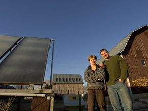 Lisa Kivirist and John Ivanko stand next to a solar thermal system that heats a greenhouse at their bed-and-breakfast.
