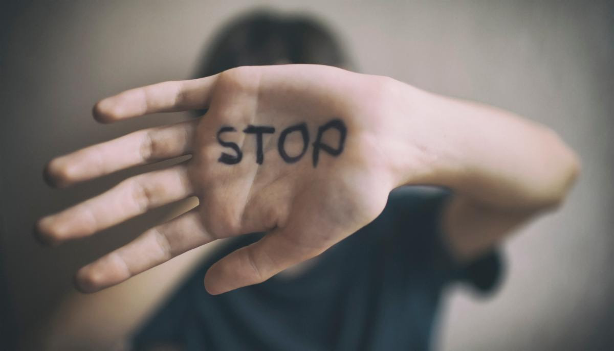 The words stop written on somebody's palm as they protect themselves 