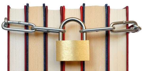A group of books is squeezed together, with a lock and chain around them.