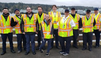 Photo of ten people wearing safety vests posing for a photograph