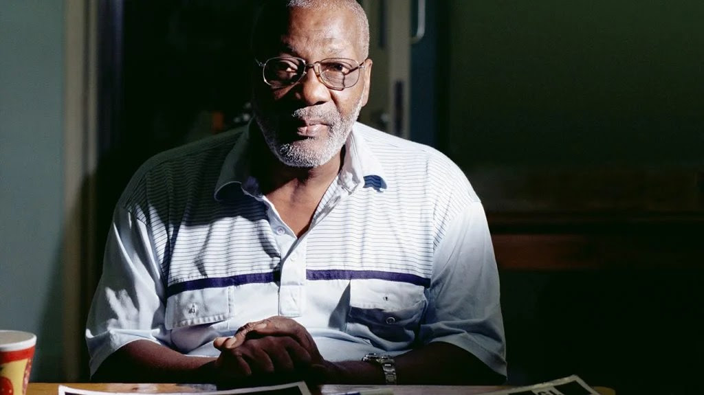 Older adult sat at a table looking at the camera