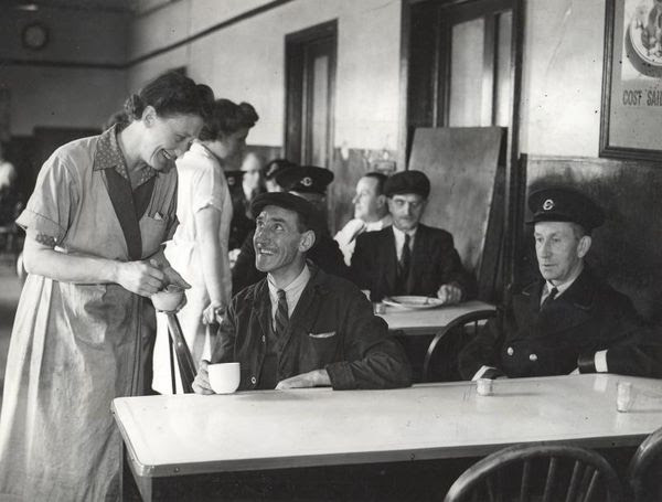 Uniformed staff smile at canteen worker pouring tea from a teapot