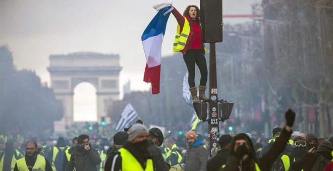 Una mujer grita consignas subida a un semáforo durante una protesta en los Campos Elíseos en París (Francia) hoy, 24 de noviembre de 2018. El ministro francés del Interior, Christophe Castaner, culpó hoy a la ultraderecha y a su líder, Marine Le Pen, de l