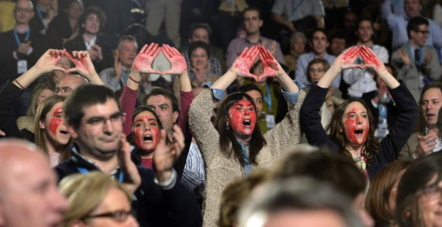 Cuatros mu8jeres con el rostro pintado de rojo gritan a favor del aborto durante el discurso de Rajoy en el Congreso del PP vasco en San Sebastián.