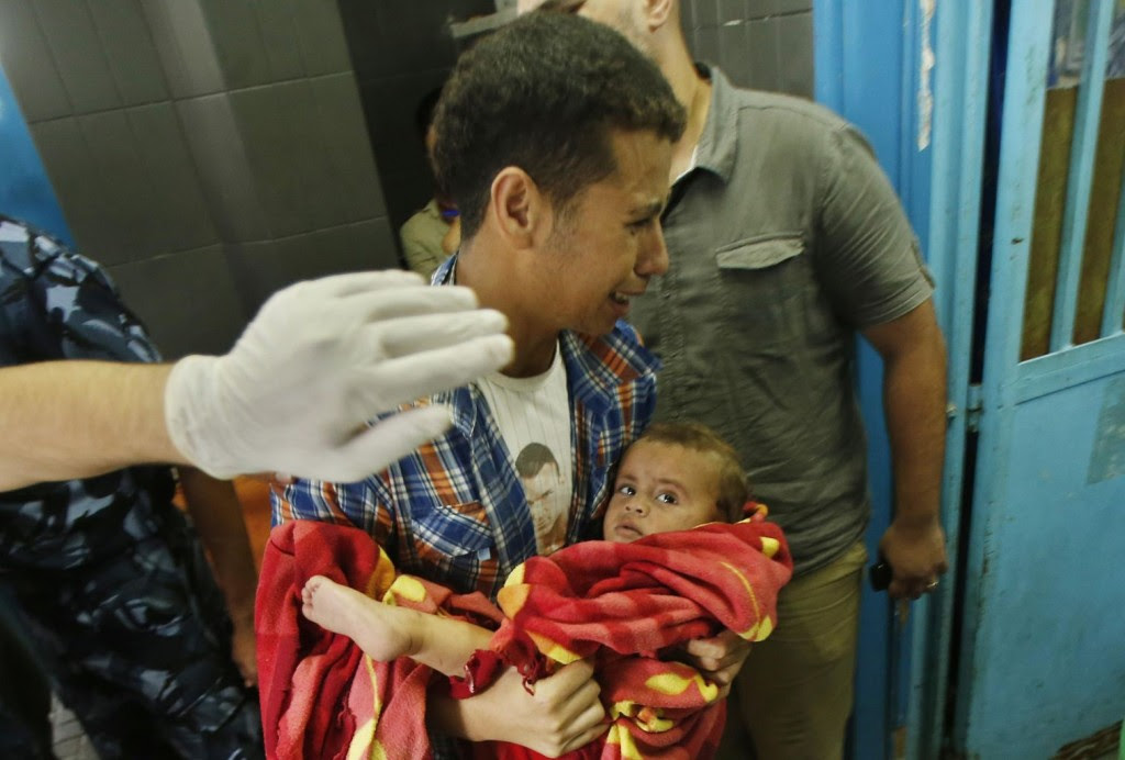 A Palestinian man reacts as he carries a boy, who medics said was wounded in Israeli shelling, at a hospital in Gaza City July 20, 2014. REUTERS/Suhaib Salem