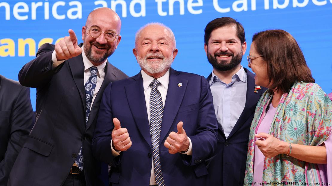 Lula faz sinal de positivo com os dois dedos polegares. Ao lado dele, Charles Michel (E) e Gabriel Boric e Alexandra Hill Tinoco (D)
