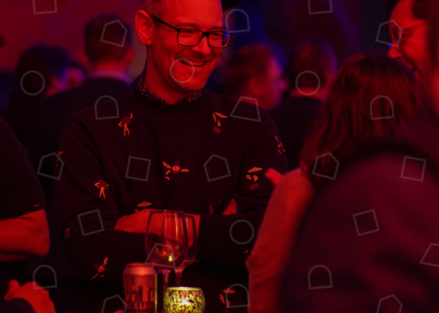 An image of a a man smiling in a group of people in a party setting