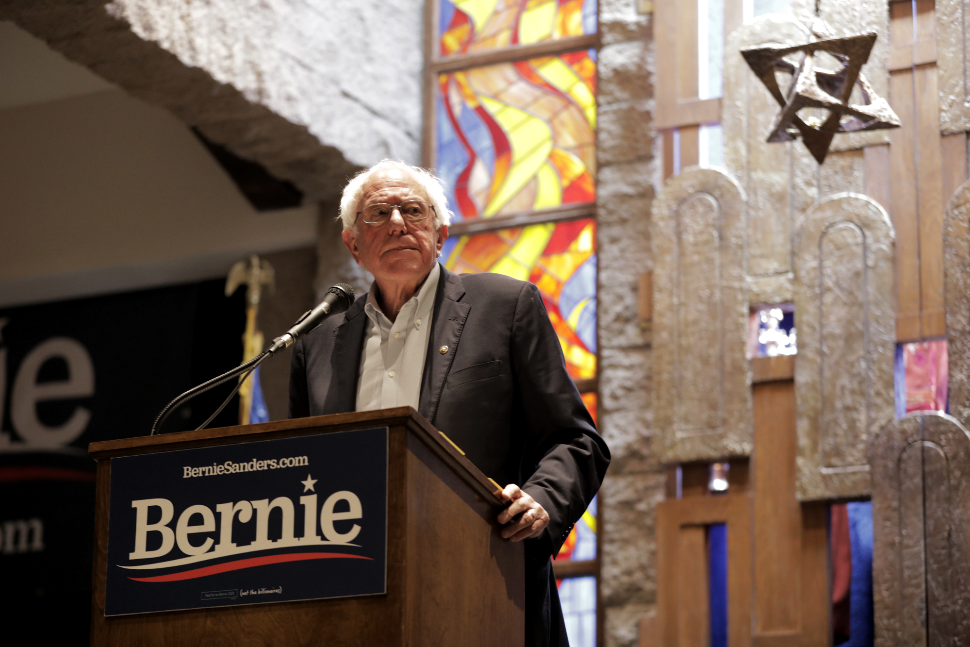 Bernie speaking at podium in front of 350-year old Torah recovered from Poland during the Holocaust