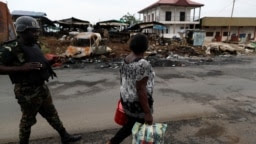 Une femme passe devant un membre de l'élite du Bataillon d'intervention rapide dans la ville de Buea, dans la région anglophone du sud-ouest, au Cameroun, le 4 octobre 2018. (Archives)