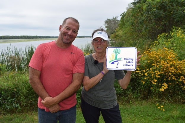 Patrick Kilbey and Karyn Niin Kitigade standing in front of Karyn’s native shoreland planting. 