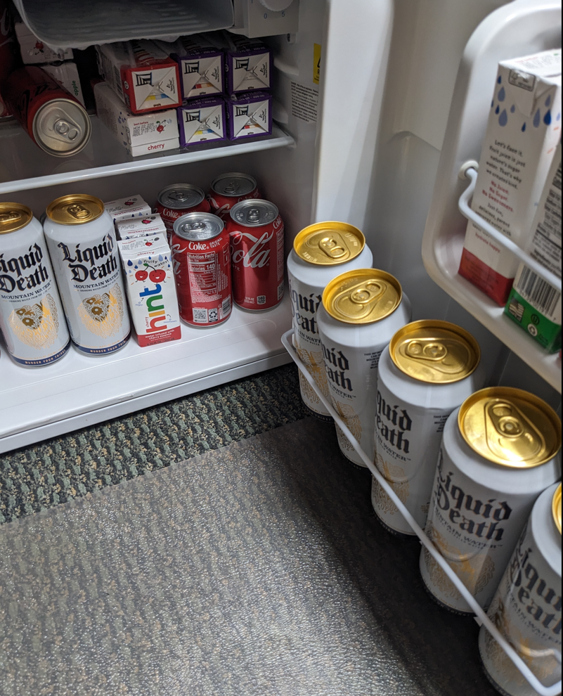 The inside of a mini fridge stocked with cans of Liquid Death water.