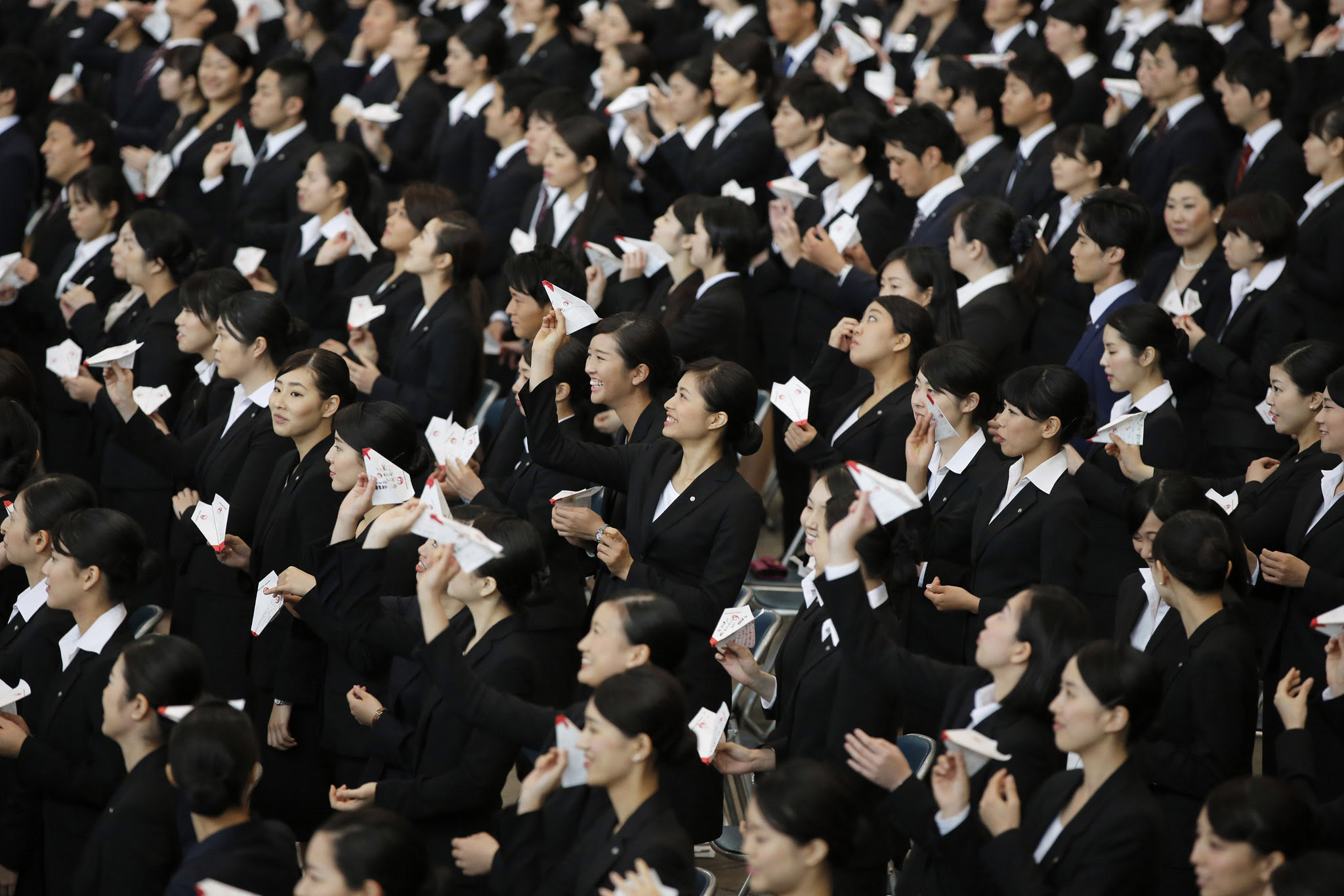 Japan Airlines Co. (JAL) group companies' new employees practice before releasing paper planes during an initiation ceremony at the company's hangar near Haneda Airport in Tokyo, Japan