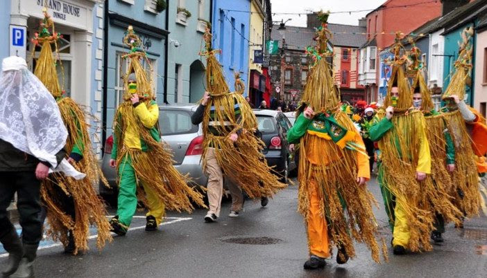wren boys in costume parading through a street