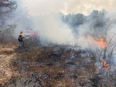 Ranger and vehicle seen through smoke during prescribed fire