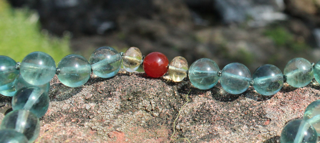 Living River gemstone necklace on rock
