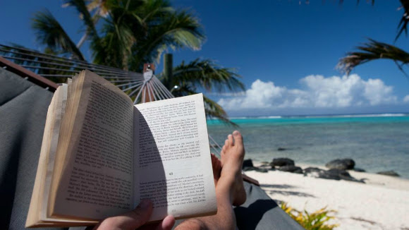 Person reading a book on a beach