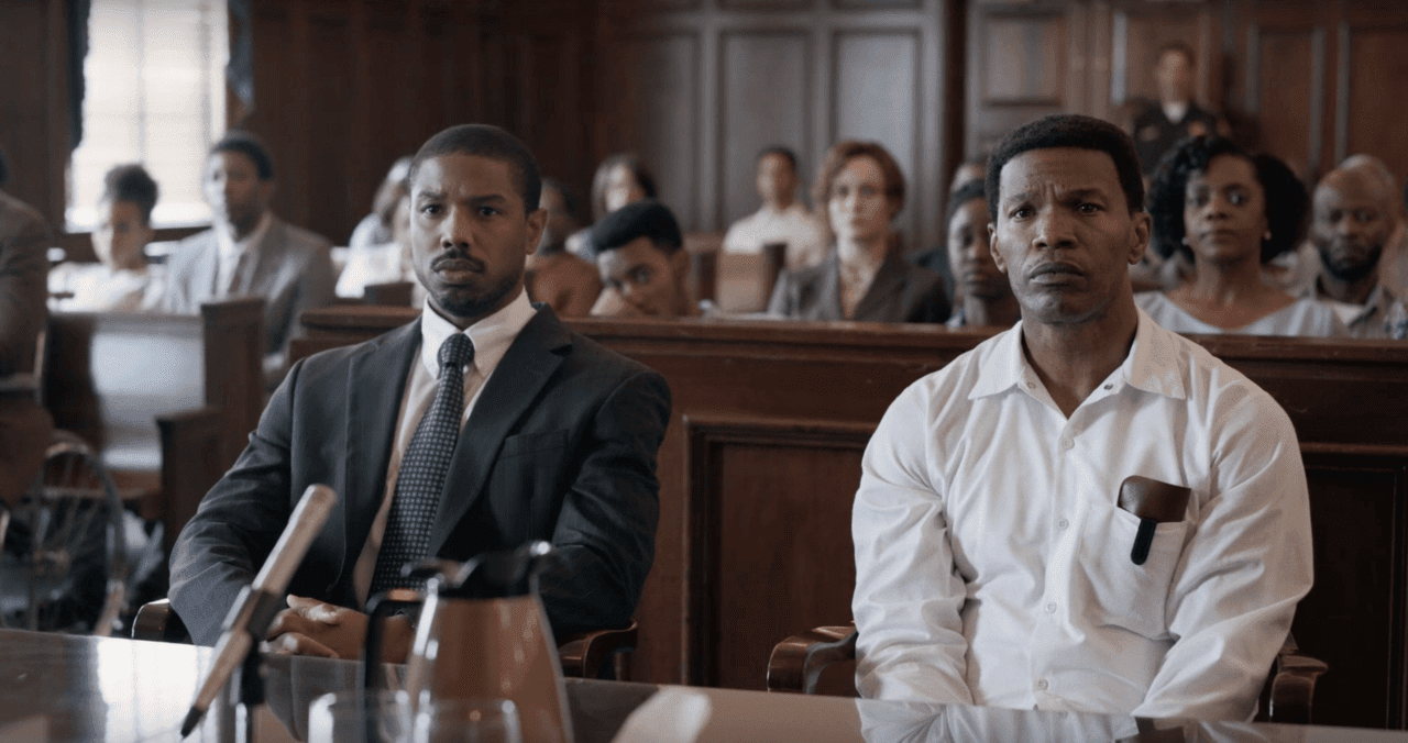 Michael B Jordan and Jamie Foxx sit in a courtroom