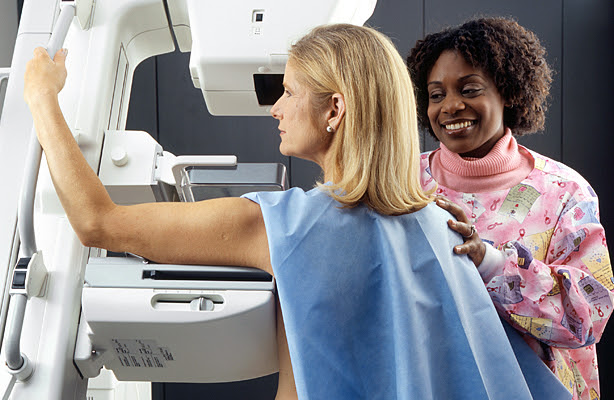 A nurse performing a mammogram on a woman.