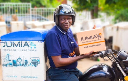 an holding a parcel while seated on a motorbike (© Jumia)