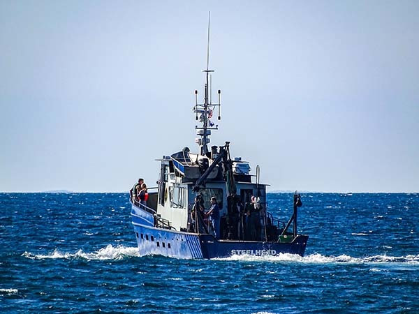 The Survey Vessel Steelhead moves out onto a blue and wavy Lake Michigan.