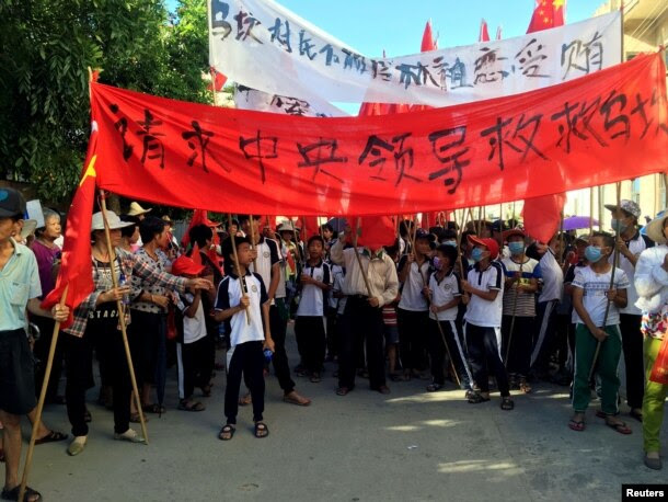 Villagers carry banners which read "Plead the central government to help Wukan" (in red) and "Wukan villagers don't believe Lin Zuluan took bribes" during a protest in Wukan, China's Guangdong province on June 22, 2016.