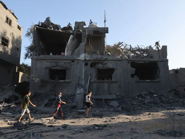 Palestinian children walking by a building reduced to rubble in Gaza.