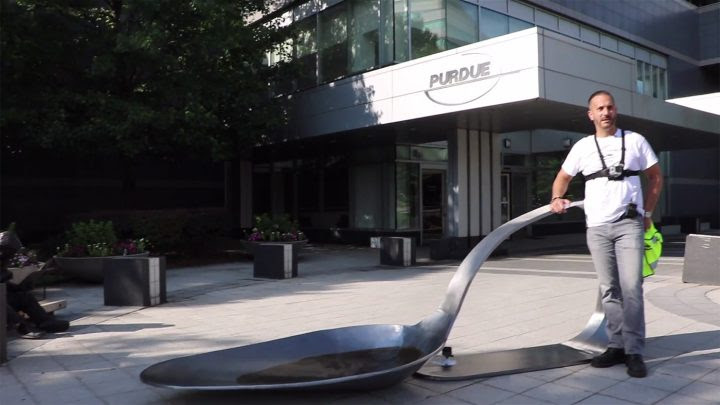 Artist Domenic Esposito stands beside an 800-pound forged steel sculpture of a burnt heroin spoon, following a guerrilla installation outside the headquarters of Purdue Pharma, makers of OxyContin. (all images pulled from live footage of the intervention, courtesy of Fernando Luis Alvarez Gallery)