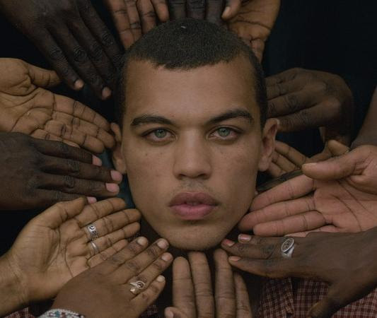 A man's face surrounded by hands