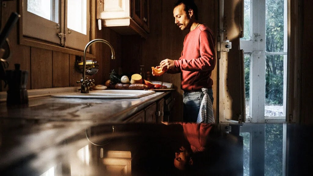 A man preparing a meal in a kitchen with various vegetables rich in fiber