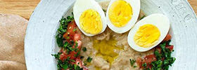 A delicious plate of humus topped with tabbouleh and three hardboiled eggs.
