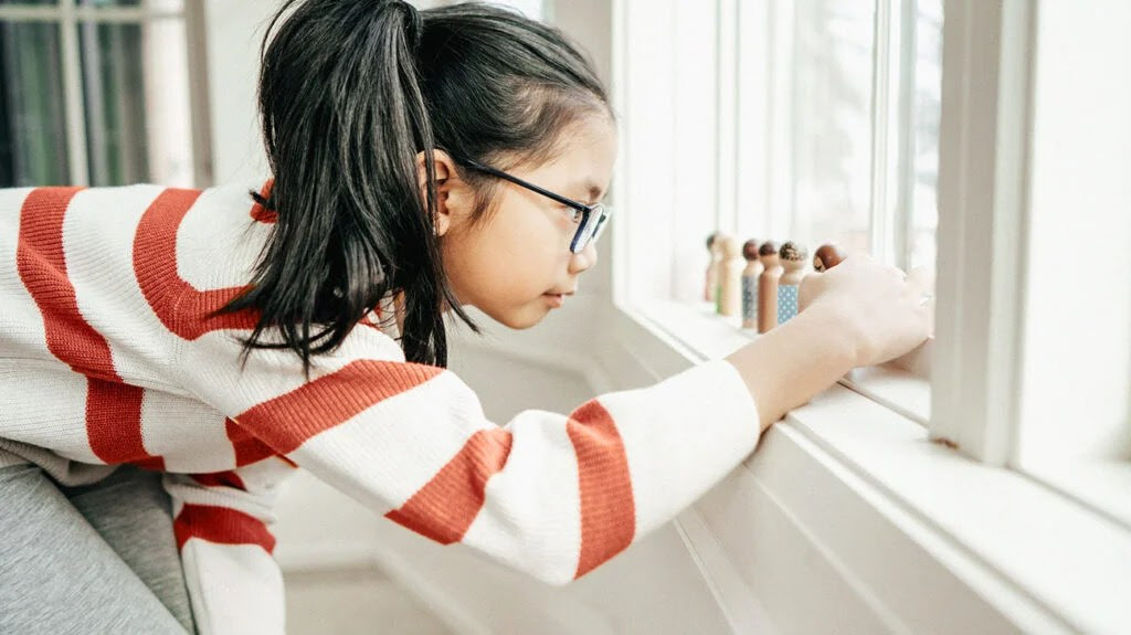 Girl playing with wooden figures representing Asperger's syndrome