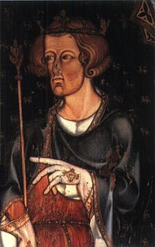 A man in half figure with short, curly hair and a hint of beard is facing left. He wears a coronet and holds a sceptre in his right hand. He has a blue robe over a red tunic, and his hands are covered by white, embroidered gloves. His left hand seems to be pointing left, to something outside the picture.