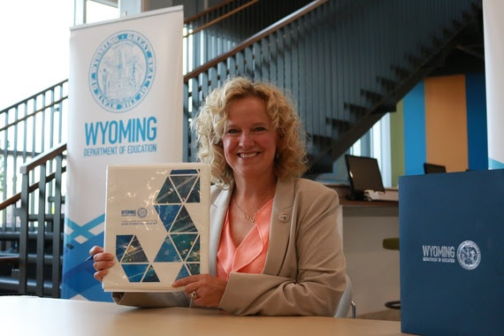 Superintendent Balow smiles and holds the signed copy of Wyoming's ESSA State Plan shortly after signing it at Laramie County Community College.