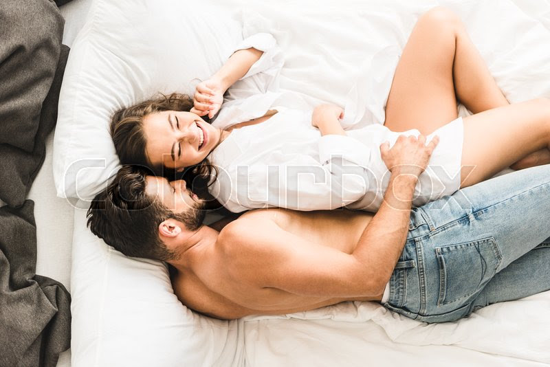 sexy couple lying on bed and laughing while man hugging girl from back |  Stock image | Colourbox