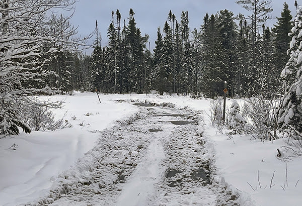 A large water hole is shown across a lengthy section of snowmobile trail.