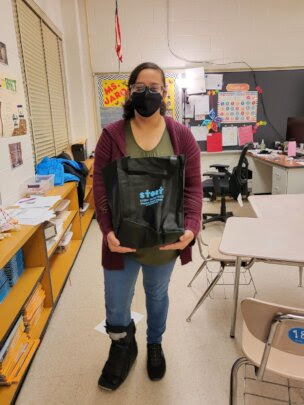A student shows off her take-home art kit in a custom tote bag Take-home art kit