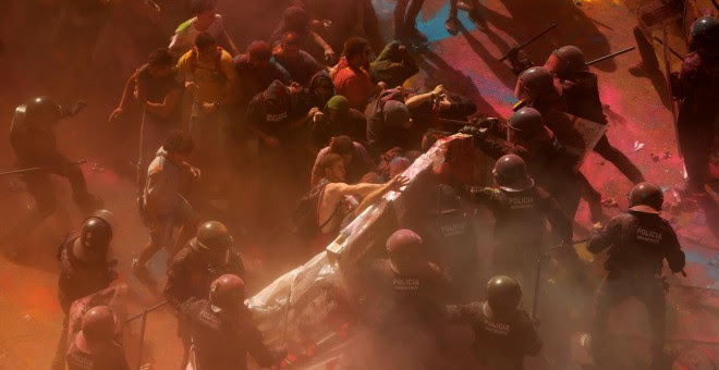 Los mossos acorralan a varios manifestantes parapetados en un material acolchado para disminuir el daño de los porrazos. | Jon Nazca / Reuters