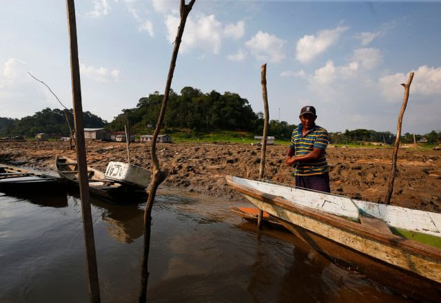 Pescador atraca barco na margem lamacenta do rio Solimes durante seca